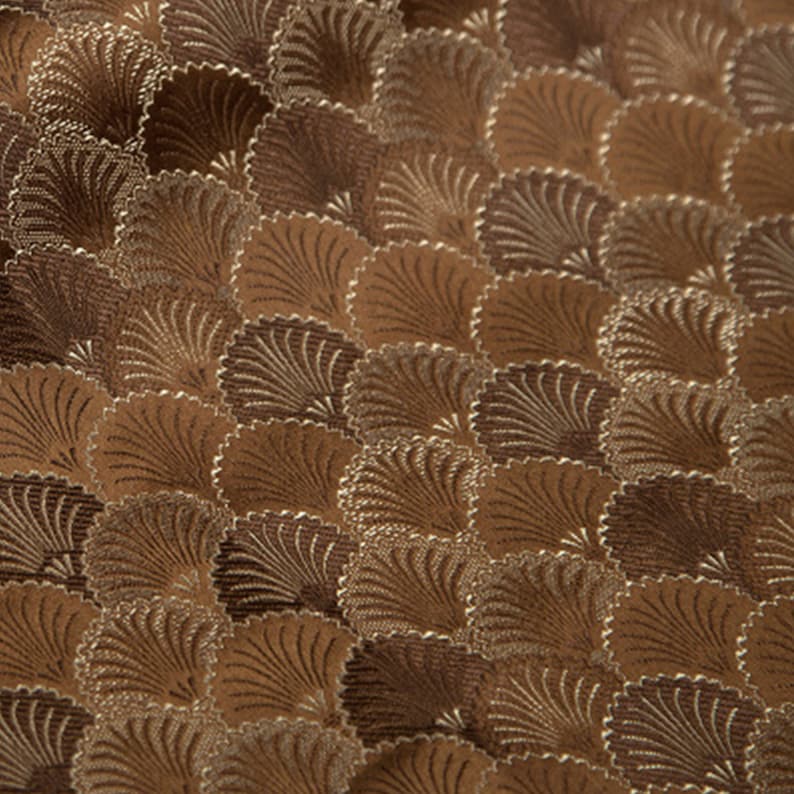 May include: A brown fabric with a repeating pattern of stylized fans. The fans are outlined in a lighter brown color and have a textured appearance.