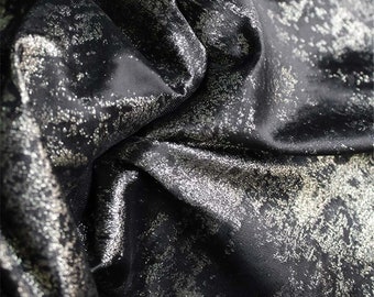 May include: Black fabric with a silver metallic finish. The fabric has a textured, marbled look.