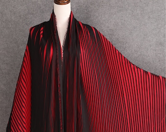 May include: Red and black striped pleated fabric. The fabric is draped over a mannequin form.