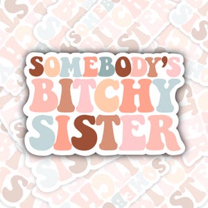 May include: A sticker with the text "Somebody's Bitchy Sister" in a retro font with pastel colors. The sticker has a white border.