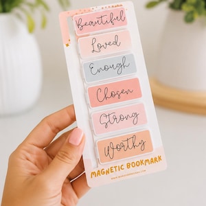 May include: A set of six rectangular magnetic bookmarks on a white backing card. Each bookmark features a pastel color and a black script word: Beautiful, Loved, Enough, Chosen, Strong, and Worthy. The bottom of the card reads MAGNETIC BOOKMARK.