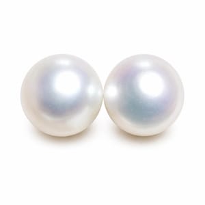 May include: Two spherical white pearls with a smooth, lustrous surface. Each pearl exhibits a subtle iridescent sheen with faint hints of blue and pink tones reflecting light across their rounded, polished surfaces against a plain white background.