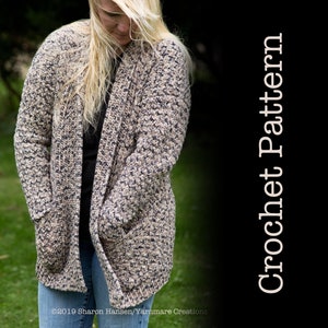 Puede incluir: Un cárdigan de crochet con un patrón moteado en tonos beige, marrón y negro. El cárdigan tiene bolsillos y un corte holgado.