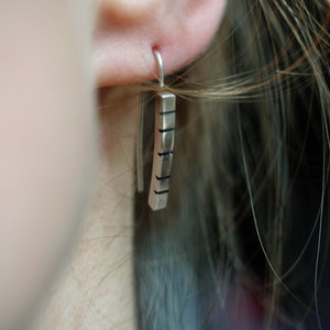 以下が含まれることがあります： 長方形でテクスチャ加工された表面を持つシルバーのドロップイヤリング