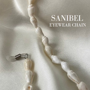 Könnte beinhalten: Eine weiße Brillenkette aus Muscheln mit einem Federschnappverschluss. Die Kette besteht aus kleinen, weißen Muscheln, die aneinandergereiht sind. Der Text "SANIBEL EYEWEAR CHAIN" ist auf weißem Hintergrund gedruckt.