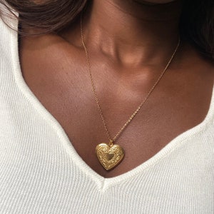 Könnte beinhalten: Eine goldene Halskette mit einem herzförmigen Anhänger mit einem filigranen Design.