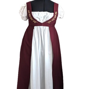 May include: A white dress with a burgundy bodice and gold embroidery. The dress has a fitted bodice and a flowing skirt.