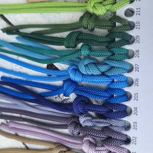 May include: A color chart of 15 different shades of cord, ranging from red to beige. The cords are tied in knots and numbered 200 to 213.