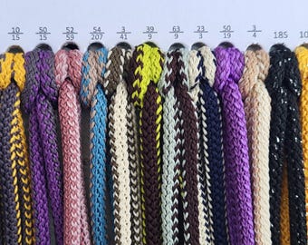 May include: A color chart featuring eighteen braided cords in various shades including gold, brown, gray, yellow, purple, pink, blue, green, and red. Each cord is labeled with a numerical code printed above it on a white background.