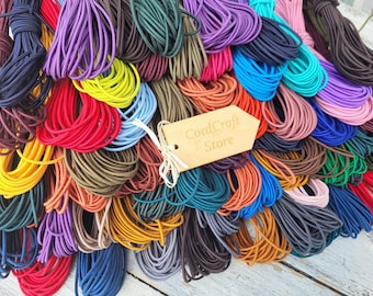 May include: A large collection of elastic cords in a wide variety of vibrant colors including red, blue, yellow, purple, green, and brown. A light-colored wooden tag with the text CordCraft Store is tied to the cords with a thin white string.