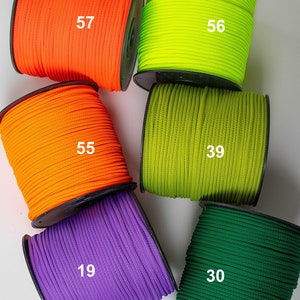 Op de afbeelding: Zes spoelen met gekleurde koord, elk met een nummer gedrukt op de zijkant. De kleuren zijn oranje, groen, paars en donkergroen.