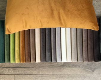 以下が含まれることがあります： 緑、茶色、灰色、白の様々な色合いの生地見本のコレクション。見本は一列に並べられ、その上にマスタードイエローの枕が置かれている。