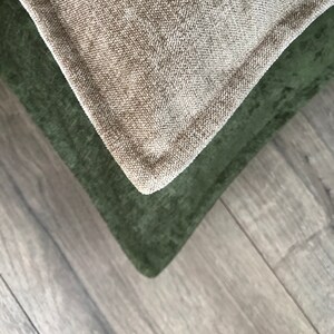 May include: Two fabric pillow covers, one in a light beige color and the other in a dark green color. The covers are made of a textured fabric and are shown overlapping each other.