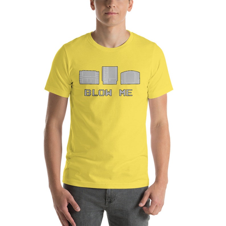 May include: A yellow t-shirt with a graphic of three video game cartridges and the text "BLOW ME".