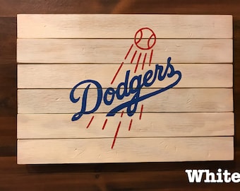May include: White wooden sign with the word "Dodgers" in blue cursive lettering and a red baseball with red rays of light coming from it.