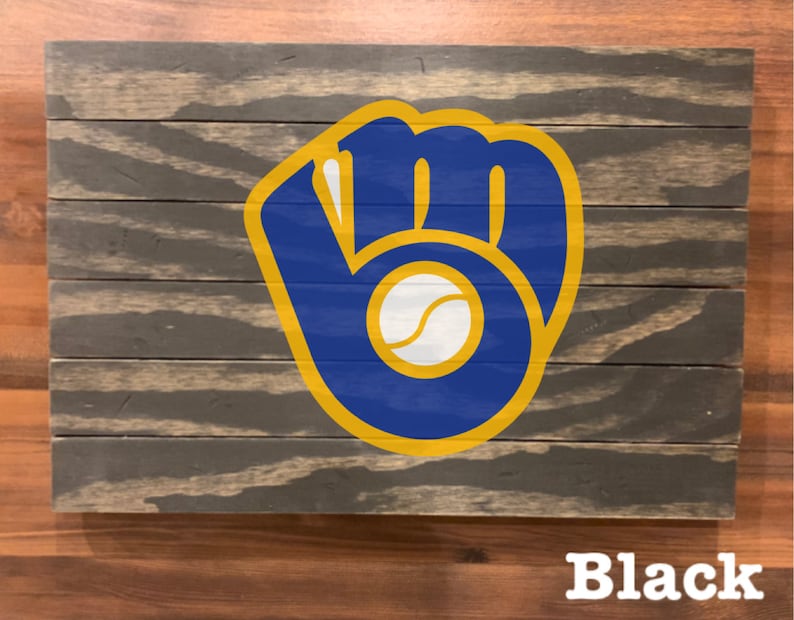 K&ouml;nnte beinhalten: Ein Holzschild mit einem blauen und goldenen Baseballhandschuh-Logo. Das Logo enth&auml;lt einen wei&szlig;en Baseball. Das Schild ist schwarz lackiert.