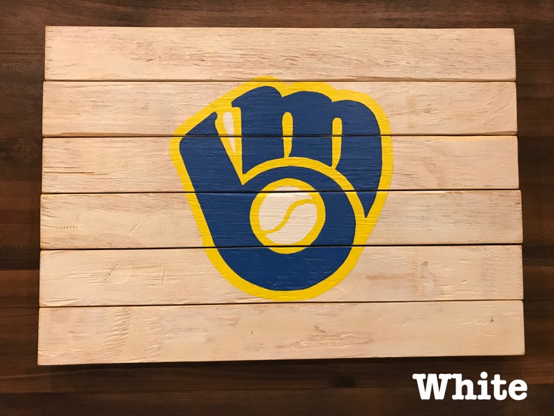 K&ouml;nnte beinhalten: Ein Holzschild mit einem bemalten Baseballhandschuh in Blau, Gelb und Wei&szlig;. Der Handschuh ist ein Logo f&uuml;r die Milwaukee Brewers.
