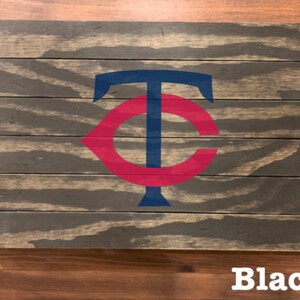 K&ouml;nnte beinhalten: Ein Holzschild mit einem roten und blauen "C" und "T" Logo. Das Schild ist schwarz lackiert und hat einen Used-Look.