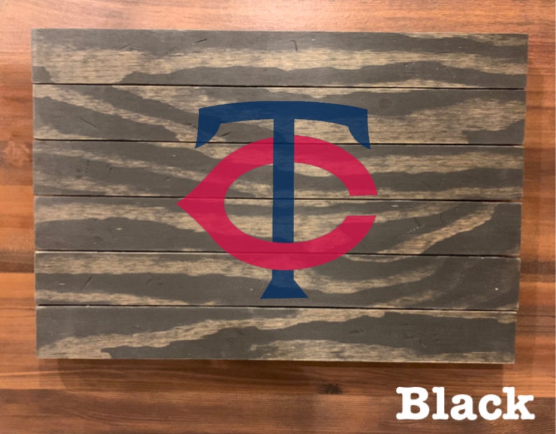 K&ouml;nnte beinhalten: Ein Holzschild mit einem roten und blauen "C" und "T" Logo. Das Schild ist schwarz lackiert und hat einen Used-Look.