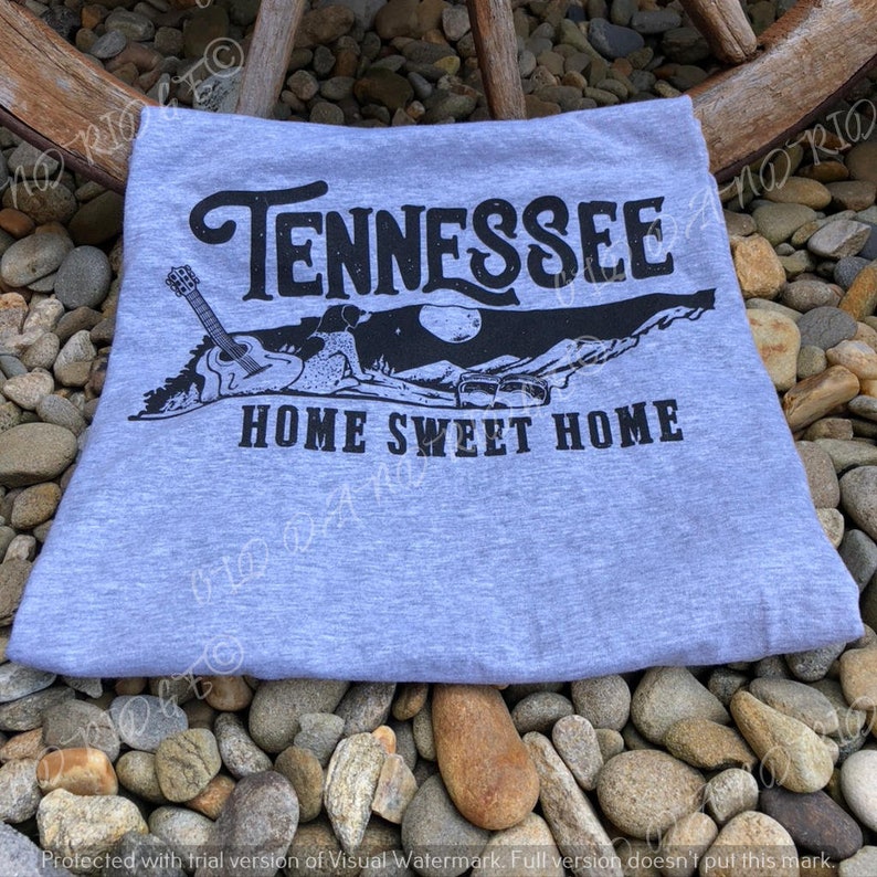 May include: Grey t-shirt with a black graphic of the state of Tennessee, a guitar, and the text "Tennessee Home Sweet Home".