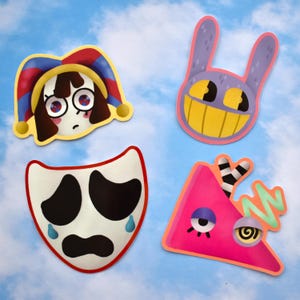 May include: Four colourful cartoon stickers on a blue sky background. The stickers include a sad-faced jester, a smiling purple bunny, a crying mask, and a pink triangle with an eye and a swirly design.