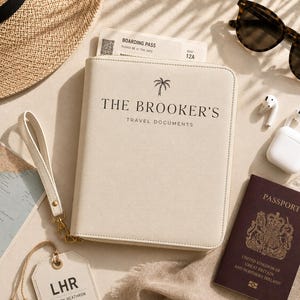 May include: A cream-colored travel document organizer with a wrist strap, featuring a palm tree icon and the text THE BROOKER'S TRAVEL DOCUMENTS. It is accompanied by a boarding pass, a dark red United Kingdom passport, and a luggage tag labeled LHR.