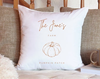 May include: White throw pillow with the text "The Jones' Farm Pumpkin Patch" in brown script font. A line drawing of a pumpkin is centered below the text.
