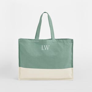 以下が含まれることがあります： 前面に「LW」のイニシャルが刺繍された、緑と白のキャンバス地のトートバッグです。