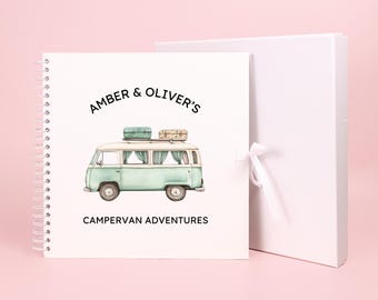 May include: A white spiral bound scrapbook with a light blue and white illustration of a vintage camper van with luggage on the roof. The text "Amber & Oliver's Campervan Adventures" is printed on the cover.