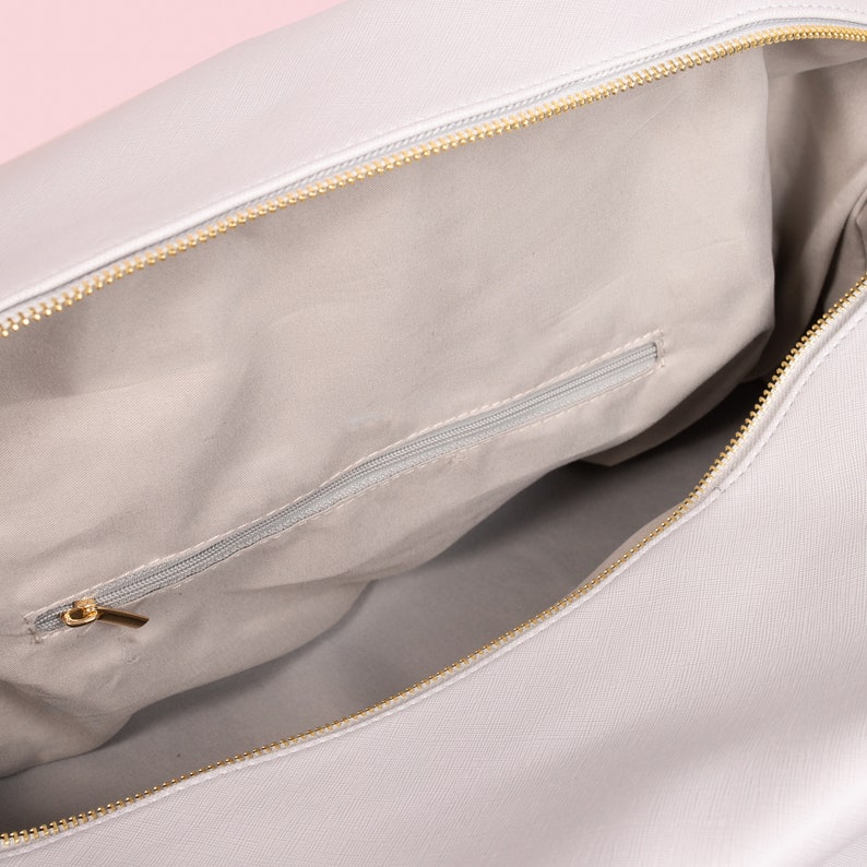 May include: A light gray travel bag with a zippered pocket inside. The bag is open and the interior lining is visible.