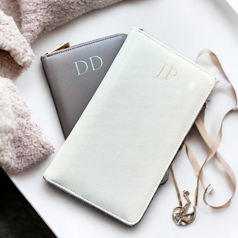 May include: Two zippered pouches, one gray with the initials "DD" in light blue and one white with the initials "JP" in gold.