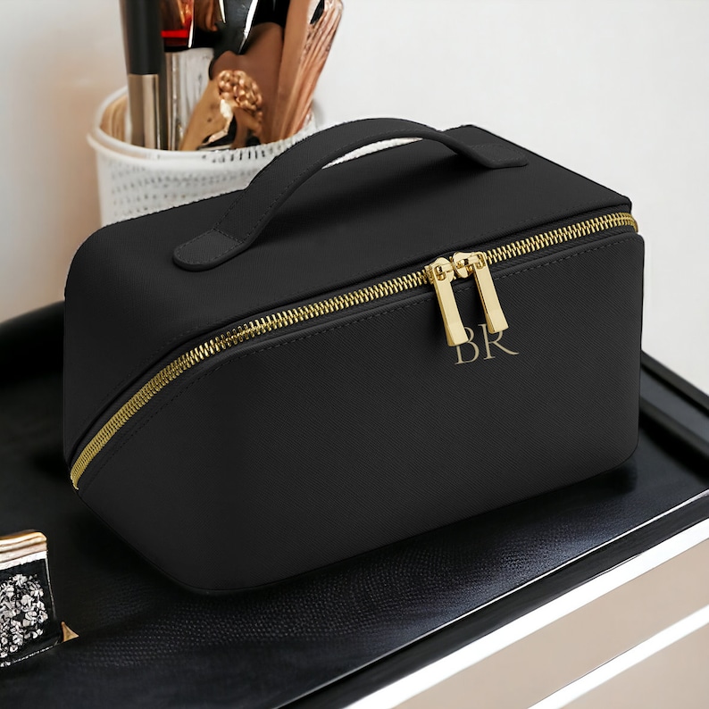 May include: Black zippered travel makeup bag with a gold zipper and handle. The bag has the initials "BR" embossed in gold on the front.
