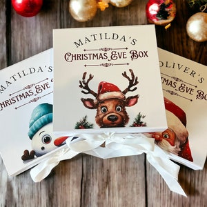 Könnte beinhalten: Drei weiße Geschenkboxen mit rotem und braunem Text und Illustrationen. Die Boxen sind mit weißem Band gebunden und tragen die Namen Matilda's Christmas Eve Box, Oliver's Christmas Eve Box und Matilda's Christmas Eve Box.