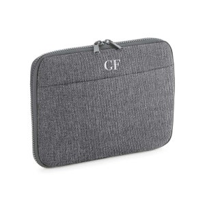 Op de afbeelding: Een grijze laptophoes met een ritssluiting en de initialen "GF" geborduurd op de voorkant.