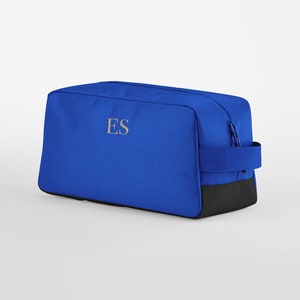 May include: A blue travel bag with a black base and a zip fastening. The bag has a handle and the initials "ES" embroidered on the front.
