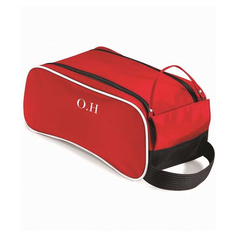 Puede incluir: Bolsa de zapatos roja con ribete blanco y detalles negros. La bolsa tiene cierre de cremallera y asa de transporte. Las iniciales "O.H" est&aacute;n bordadas en la parte delantera de la bolsa.