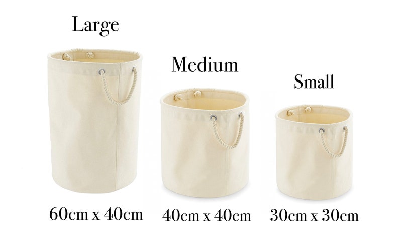 May include: Three cylindrical off-white canvas storage baskets with rope handles. The large basket is 60cm x 40cm, the medium basket is 40cm x 40cm, and the small basket is 30cm x 30cm. Each basket features metal grommets for the rope handles.