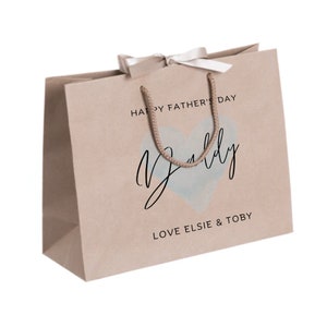 May include: A brown paper gift bag with a white ribbon and a blue watercolor heart with the text "Daddy" in black script. The bag also has the text "Happy Father's Day" and "Love Elsie & Toby".