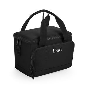 Könnte beinhalten: Schwarze isolierte Lunchtasche mit einem Reißverschluss-Hauptfach und einer Vordertasche. Die Tasche hat einen oberen Griff und das Wort "Dad" in Weiß auf der Vordertasche aufgedruckt.