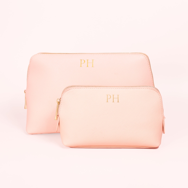 May include: Two pink zippered cosmetic bags with gold zippers and the initials "PH" embroidered in gold on the front.