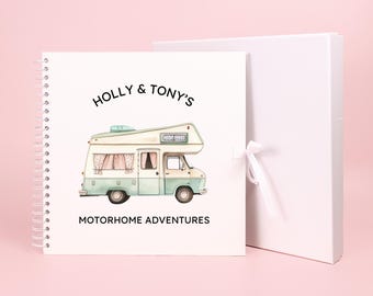 May include: A white scrapbook with a spiral binding. The cover features a cartoon illustration of a blue and white camper van with the text "HOLLY & TONY'S MOTORHOME ADVENTURES".