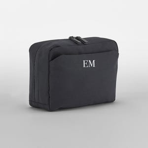 May include: Black zippered travel toiletry bag with a front pocket and the initials "EM" embroidered in white.