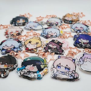Puede incluir: Una colecci&oacute;n de llaveros de acr&iacute;lico transparente con varios personajes de anime estilo chibi con cabello y atuendos coloridos. Cada llavero est&aacute; unido a un cierre en forma de estrella de oro rosa e incluye el texto SHIROUU_KUN impreso.