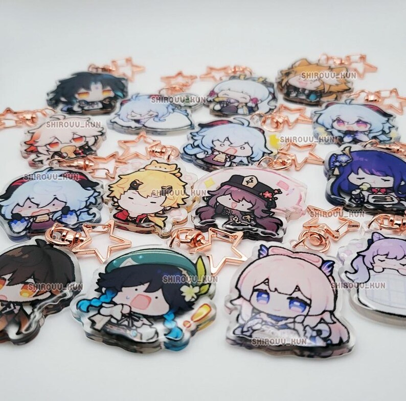 Puede incluir: Una colecci&oacute;n de llaveros de acr&iacute;lico transparente con varios personajes de anime estilo chibi con cabello y atuendos coloridos. Cada llavero est&aacute; unido a un cierre en forma de estrella de oro rosa e incluye el texto SHIROUU_KUN impreso.