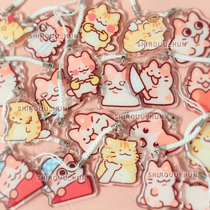 May include: A collection of clear acrylic cat charms featuring various cartoon illustrations of cats in orange, white, and pink colors. Each charm includes a white cord strap and the text SHIROUU_KUN printed on the surface of the acrylic material.