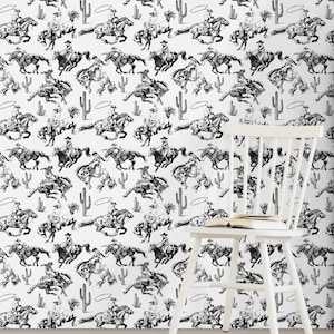 May include: Black and white repeating pattern wallpaper featuring cowboys riding horses with lassoes. The pattern includes cacti and rope circles. A white chair with a book on it is in the foreground.