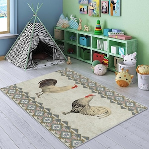May include: A cream-colored rug with a geometric pattern in shades of brown, blue, and pink. Two roosters are featured on the rug, one facing left and one facing right. The rug is on a wooden floor in a room with a teepee and a bookshelf.