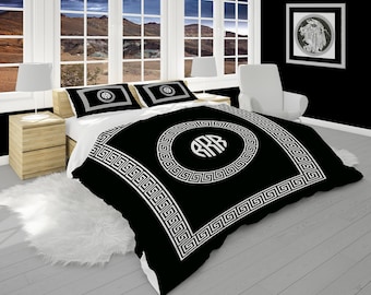 May include: Black and white duvet cover with a Greek key border and a monogram in the center. The monogram is surrounded by a circle.