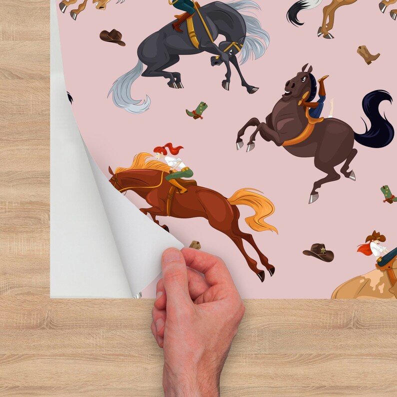 Peut inclure: Fond rose avec un motif r&eacute;p&eacute;t&eacute; de chevaux de dessin anim&eacute; et de cavaliers. Les chevaux sont bruns, noirs et blancs. Les cavaliers portent des v&ecirc;tements color&eacute;s. Il y a aussi quelques chapeaux de cow-boy et des bottes &eacute;parpill&eacute;es.