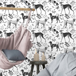 May include: A white background with a black and white repeating pattern of stylized dogs. The dogs are in various poses, some are running, some are standing, and some are lying down. There is a pink hammock hanging in the foreground. Two white candles are on a wooden table in the foreground.